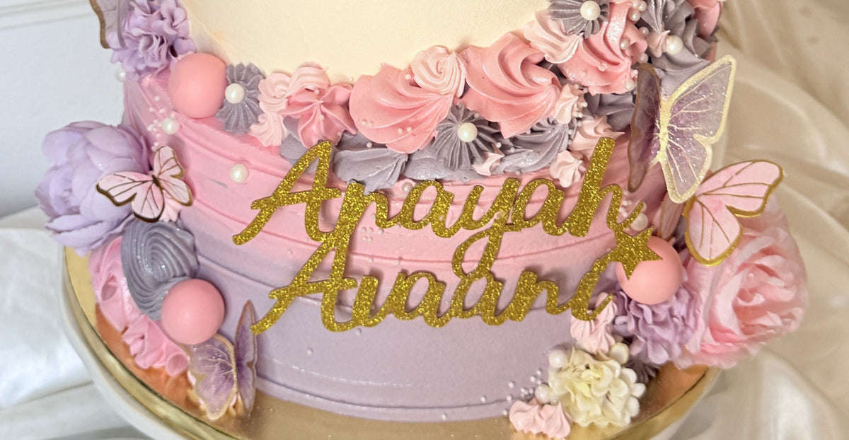 Close up of the lilac base with gold glitter names and butterflies, custom cakes East London, Romford and Ilford.