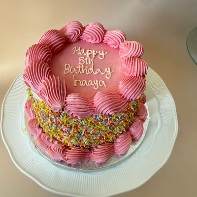 Pink buttercream birthday cake with shell piping and a rainbow sprinkle band, custom cakes East London, Romford and Ilford
