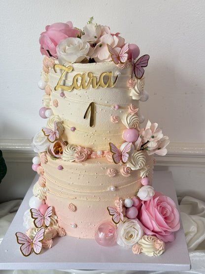 Angled view of the two-tier pink floral first birthday cake, custom cakes East London, Romford and Ilford.