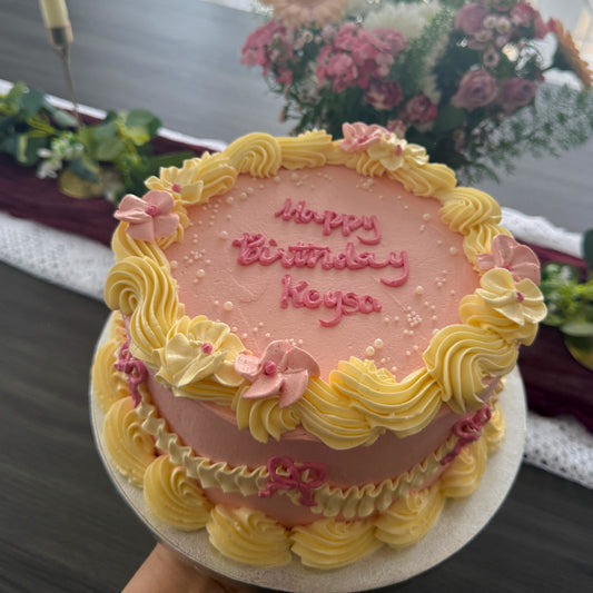 Pink and yellow vintage buttercream cake with piped flowers and bows, custom cakes East London, Romford and Ilford.