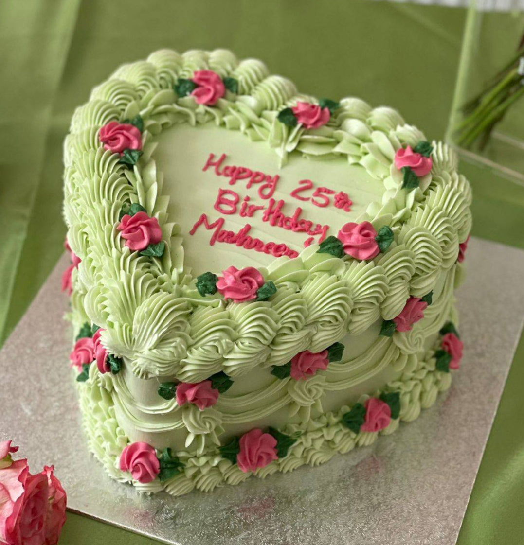 Same-day heart-shaped birthday cake in pastel green with floral piping, available in East Ham and Harold Hill.