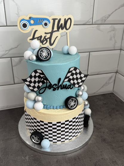 Two-tier Two Fast race car birthday cake with checkered flags and name topper, custom cakes East London, Romford and Ilford.