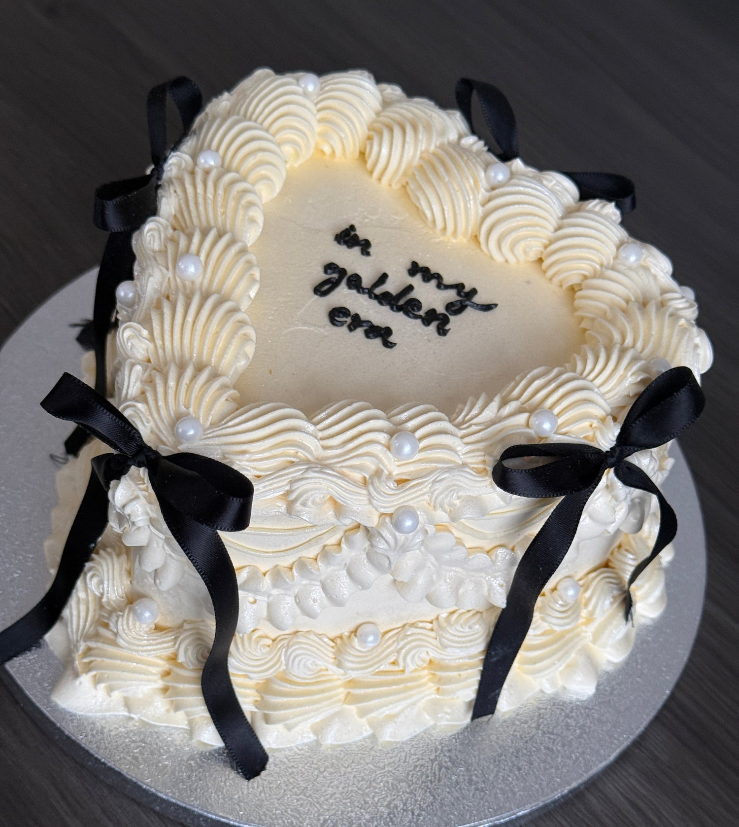 Vintage bow heart cake with ivory buttercream piping, black ribbon bows, and pearl decorations – available for same day and next day cake delivery in Romford and East London from CakeTrays.co.uk.