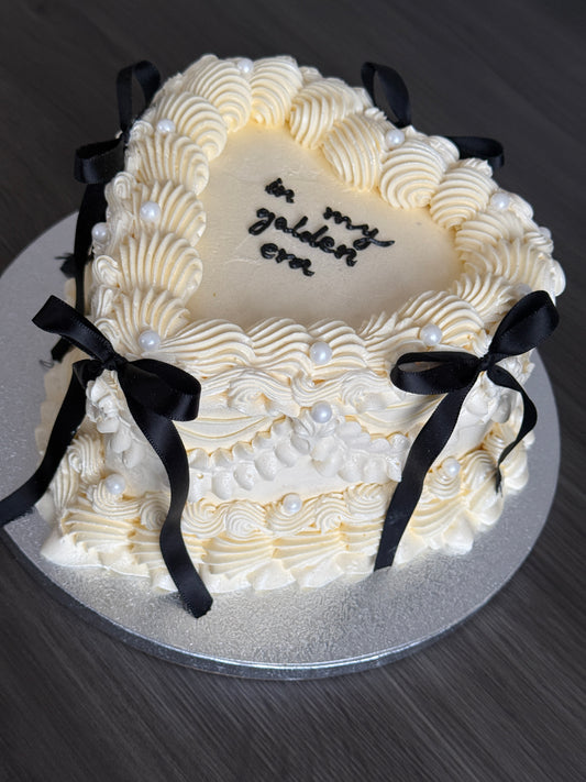 Vintage bow heart cake with ivory buttercream piping, black ribbon bows, and pearl decorations – available for same day and next day cake delivery in Romford and East London from CakeTrays.co.uk.