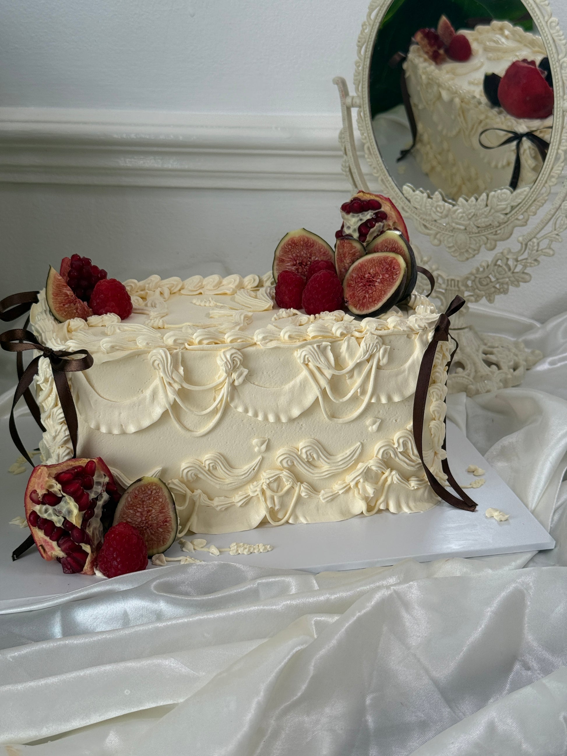 Overhead view of a vintage cream piped cake decorated with figs, raspberries and pomegranate — Cake Trays East London