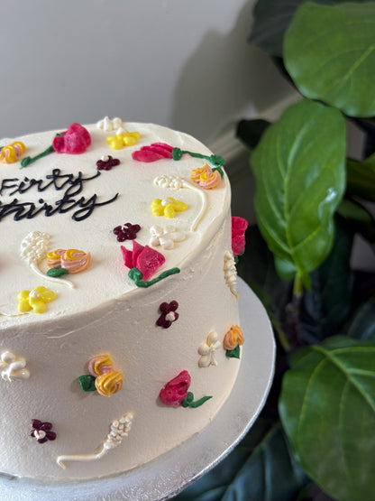 White buttercream celebration cake with hand piped pastel wildflowers, custom cakes East London, Romford and Ilford.