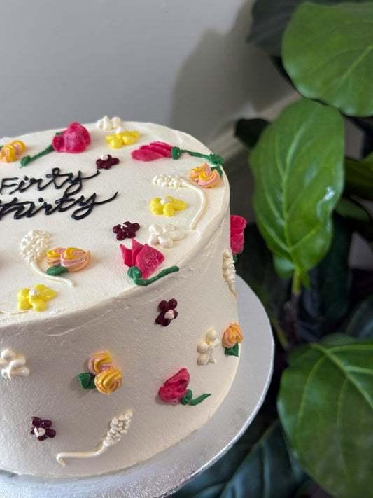 White buttercream celebration cake with hand piped pastel wildflowers, custom cakes East London, Romford and Ilford.